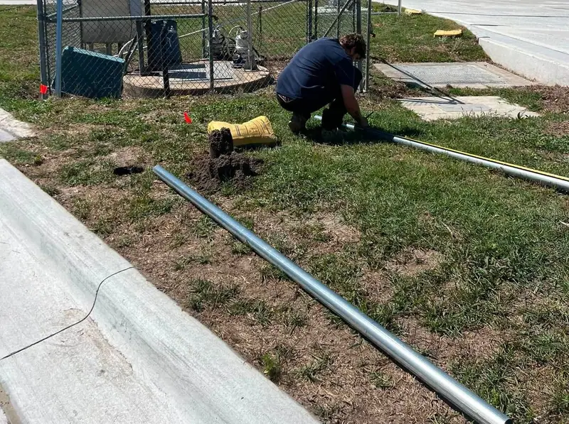 A Southern Line crew member setting galvanized chain link posts at a commercial lot