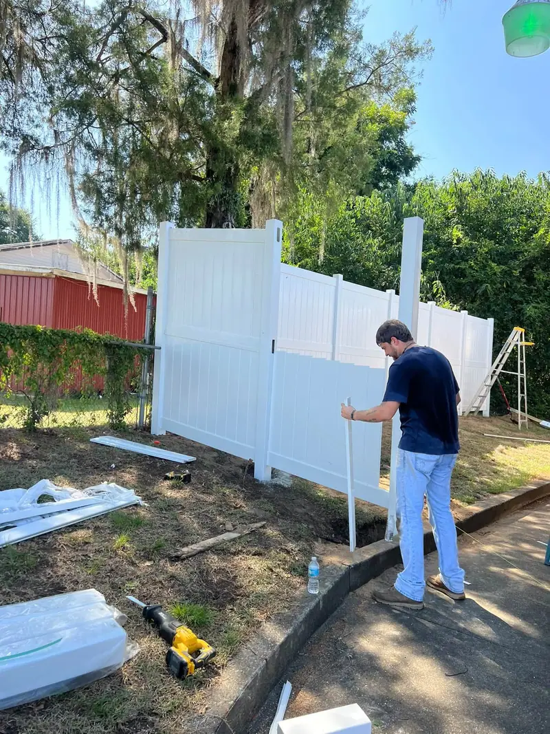 A Southern Line Fence & Finish crew member setting white vinyl privacy fence panels