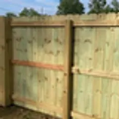 A tall new pine privacy fence seen from the rail side, under a blue sky