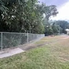 Galvanized chain link fence beside a concrete walk and lawn